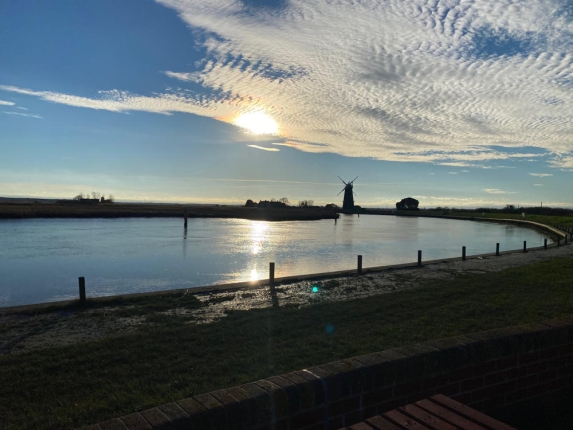 Sunset scene, with a river and a windmill in the background