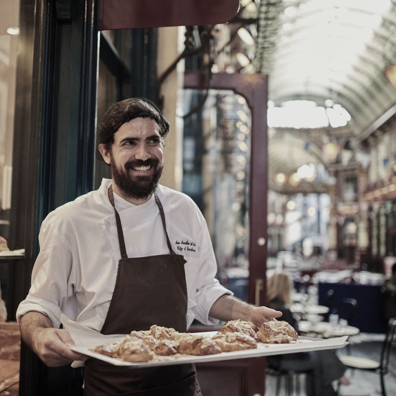 Man cheerfully holding a tray of pastry