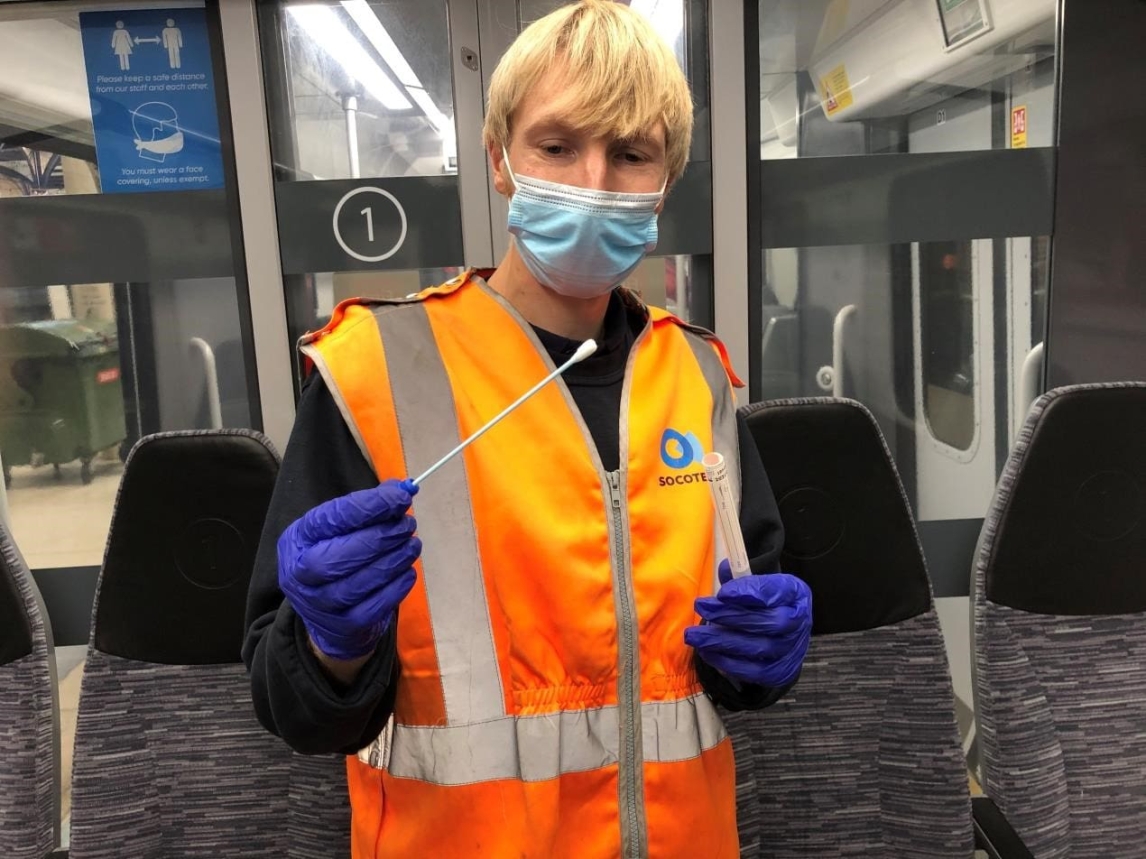 Woman in high vis jacket holding covid testing equipment 